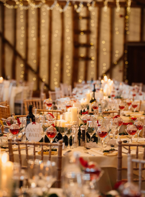 The barn reception with fairy-lit beams and candlelit round tables