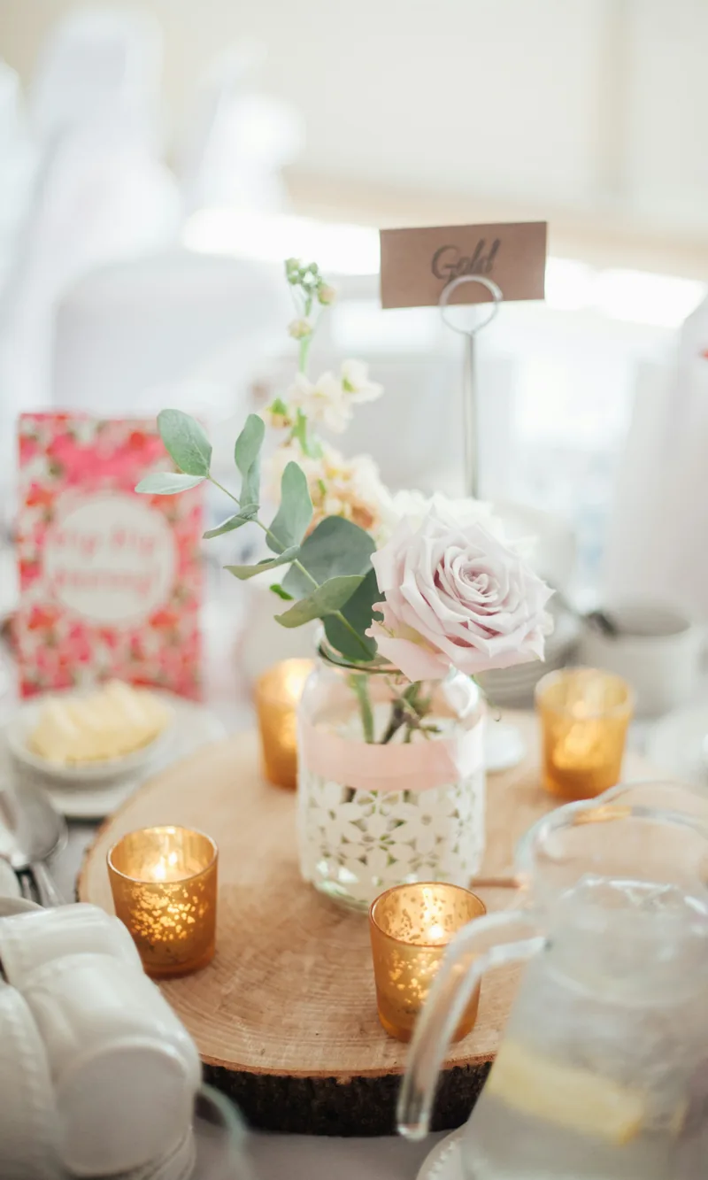 A soft pink rose centrepiece with candles on a pastel table