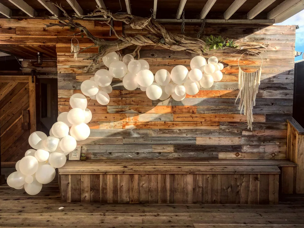 A garland of white balloons against a rustic timber wall