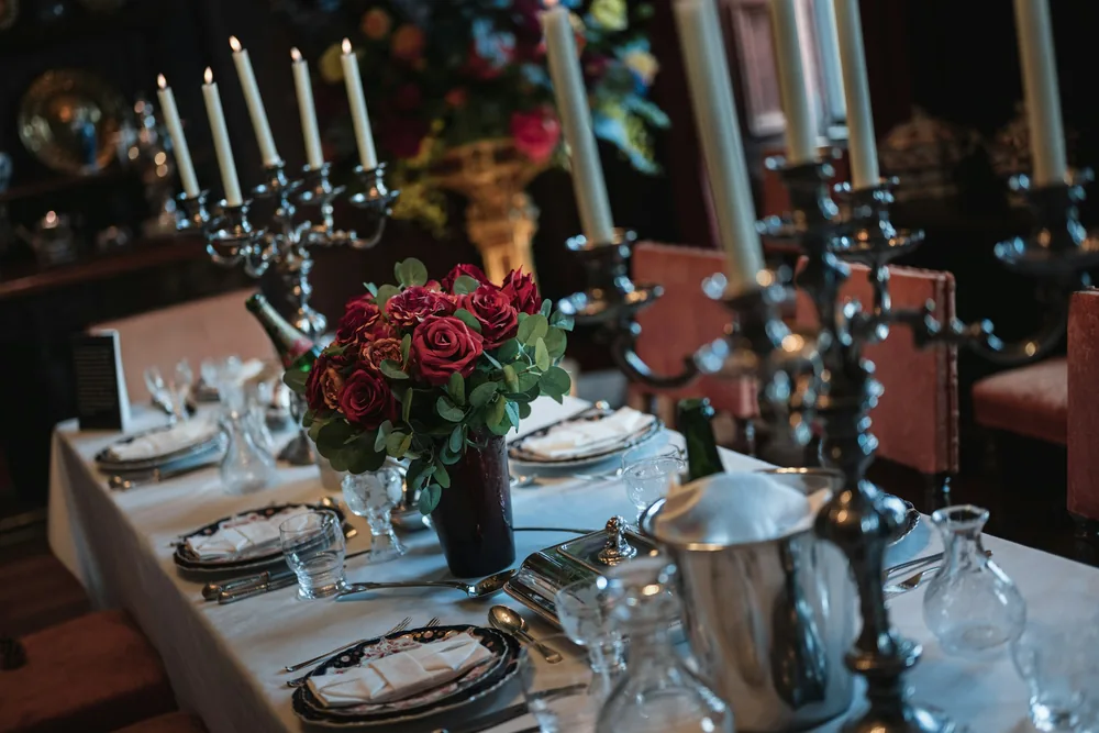 A formal dinner table set with silver candelabras and red roses