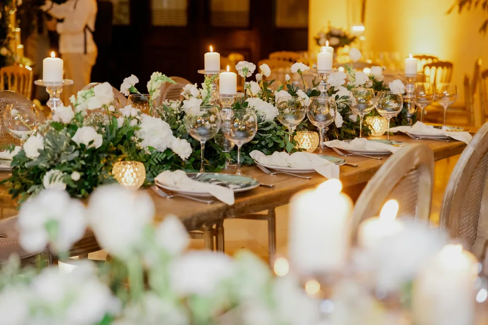 A candlelit long table dressed with white flowers and greenery