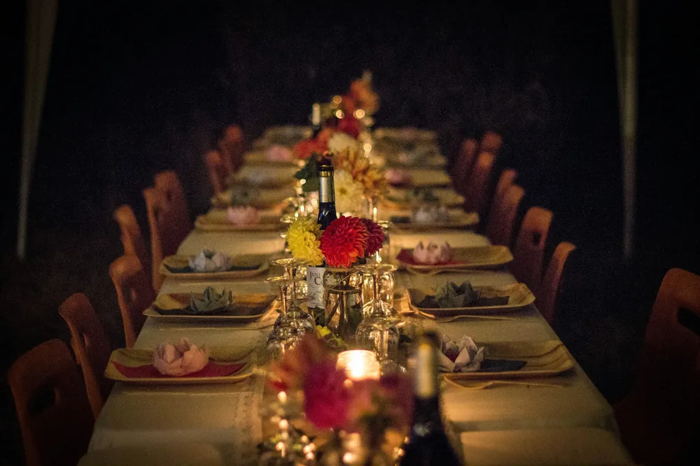 A long dinner party table glowing with candles and flowers