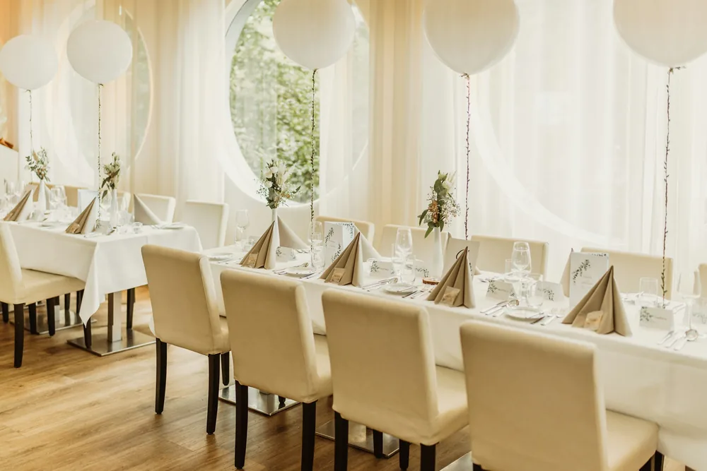 A long celebration table dressed in white with white balloons