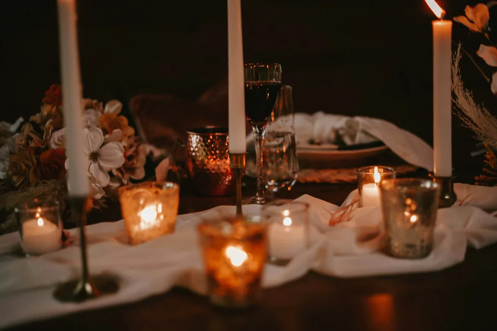 Candles and glass holders glowing on a linen-dressed table