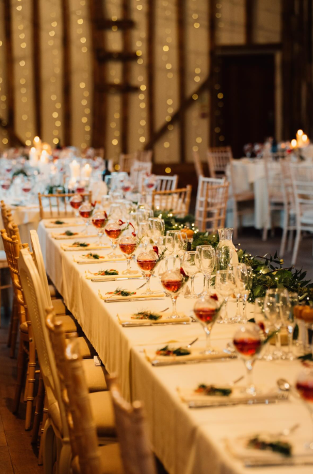 A long table running the length of the barn, set with candles and greenery