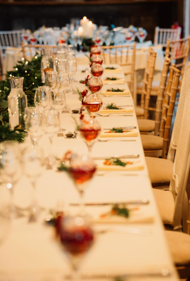A long wedding table at Villiers Barn set with red baubles, pine and candlelight