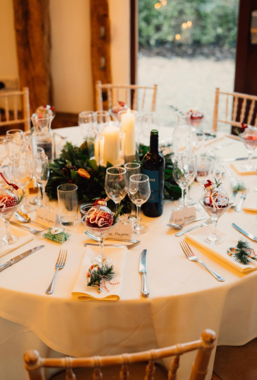 A round table set with a pine and candle centrepiece and personalised baubles